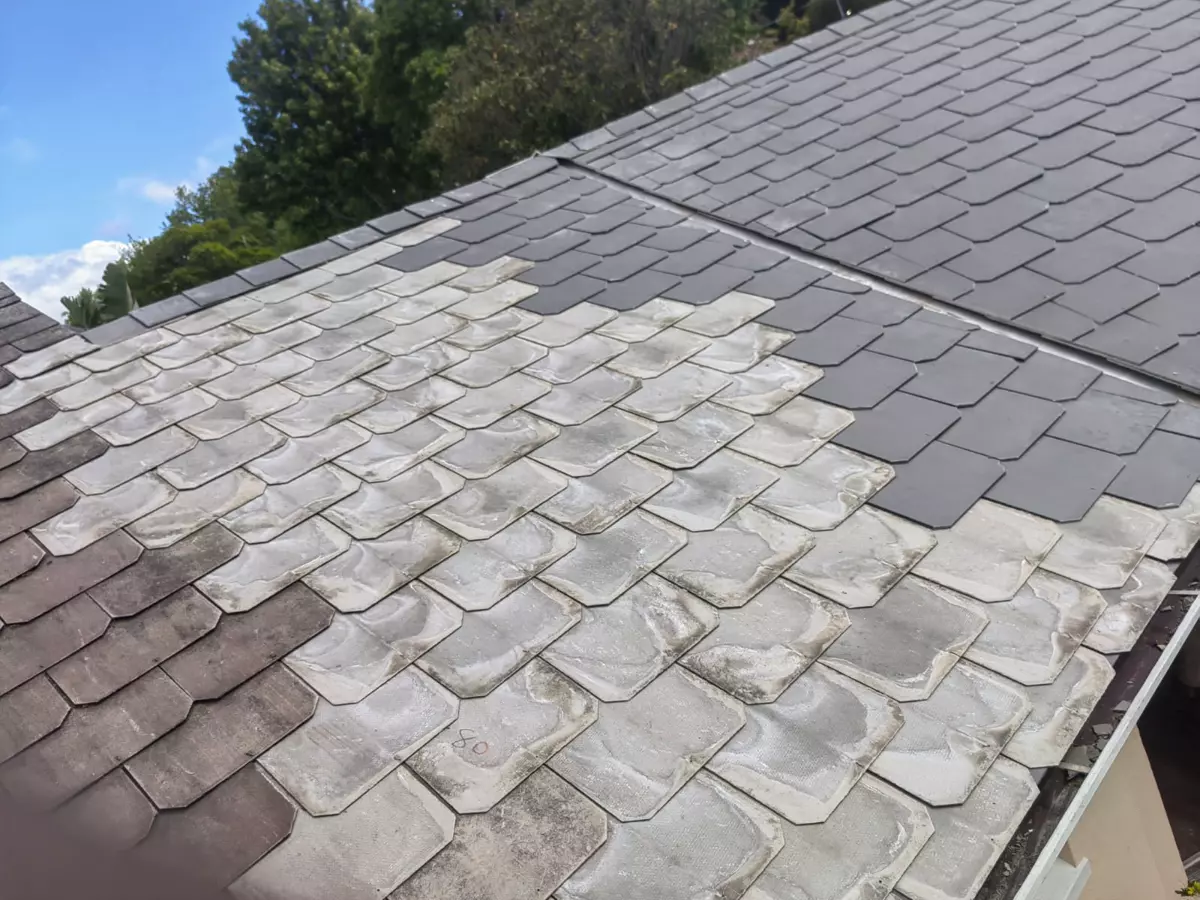 Residential roof undergoing cleaning, contrasting weathered and newly cleaned shingles