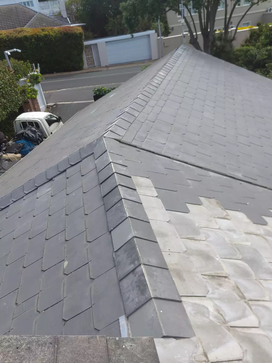 Slate roof under repair with dark grey and lighter weathered tiles