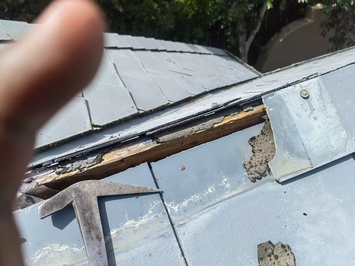 Damaged roof repair showing exposed wooden framing