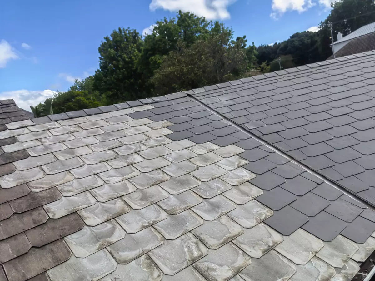 Roofing repair showing weathered shingles alongside newly installed dark tiles